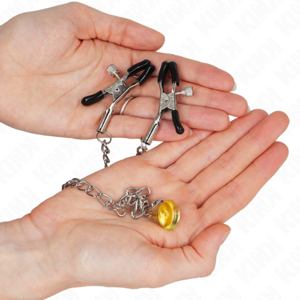 Twee Kink Nipple Grip tepelklemmen, verbonden door een ketting met een goudkleurig belletje